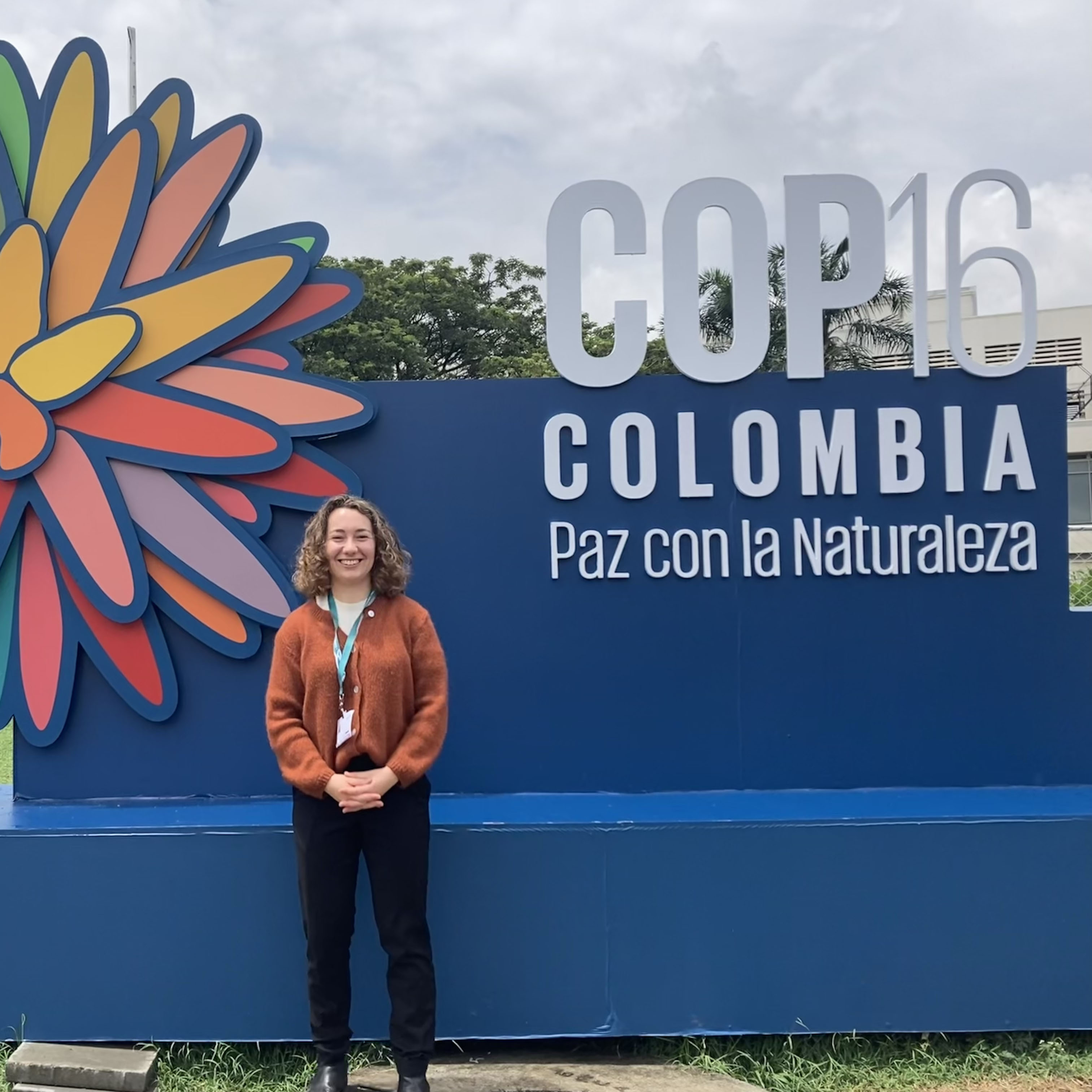 Magali smiling in front of COP16 sign in Cali Colombia