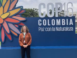 Magali smiling in front of COP16 sign in Cali Colombia